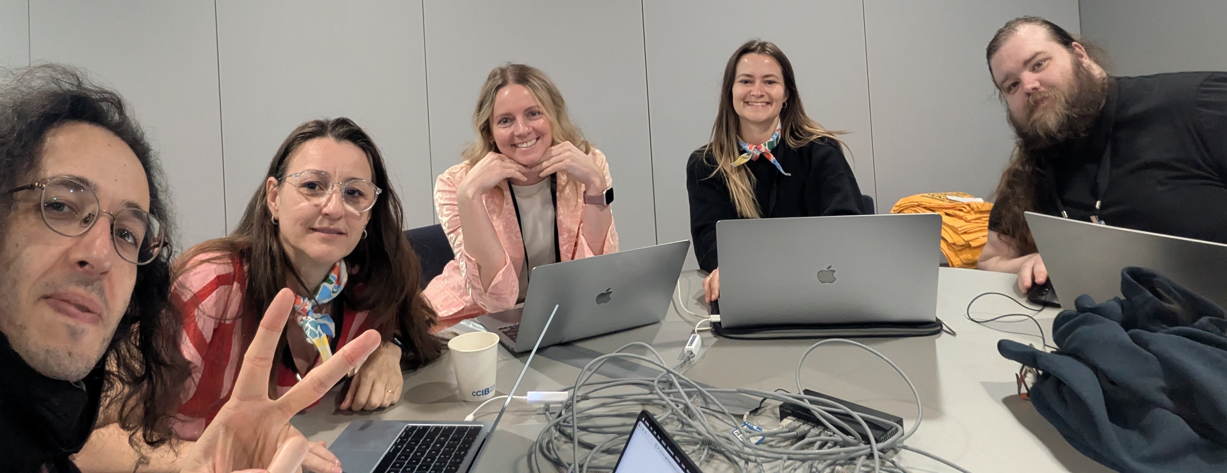 Five tired but smiling faces working behind laptops, from left to right: Pedro, Heloisa, Alex, Maxi, and Jas